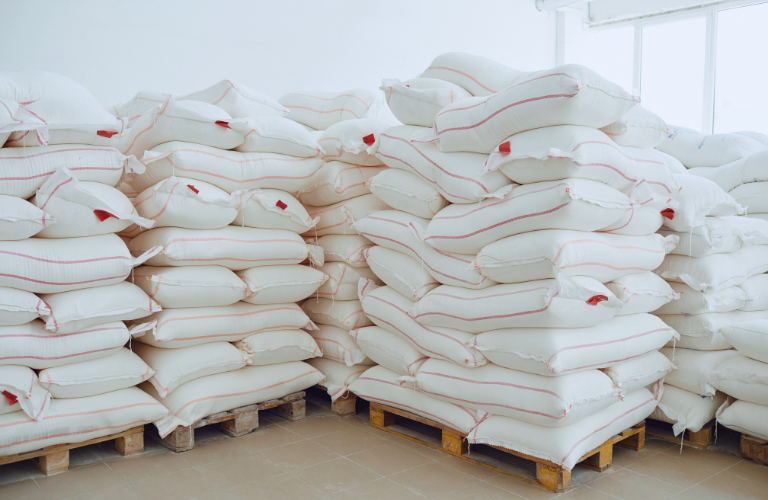 Xếp chồng các bao đường lên nhau và có tấm pallet kê ở dưới để giảm tác động của độ ẩm